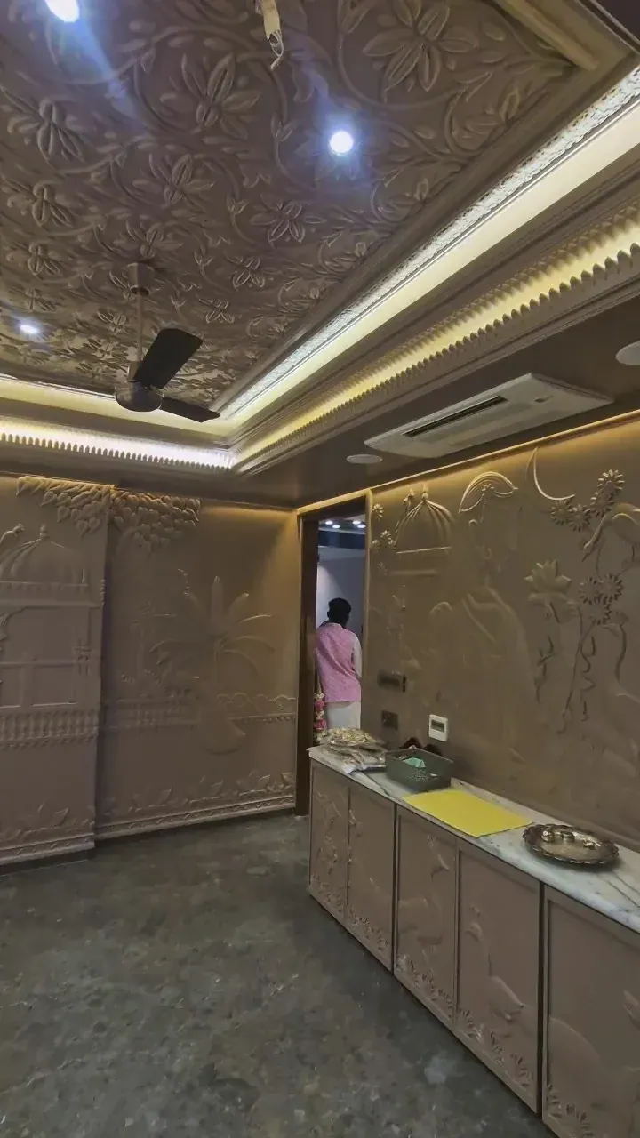 Pooja room under construction with carved stone relief walls, carved storage cabinets and cove-lit ceiling